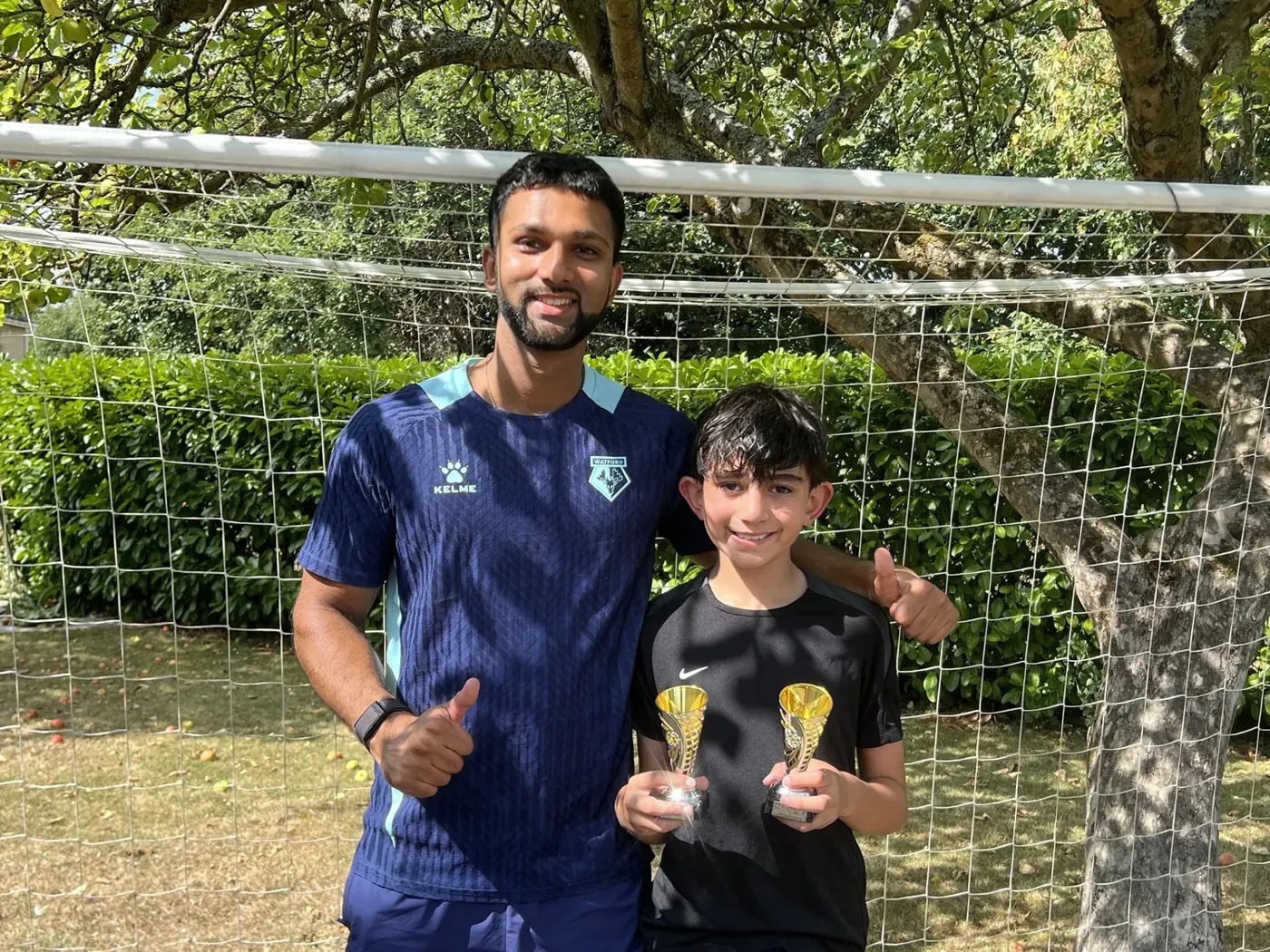 Head Coach Farhan Kharawala with a young player holding trophies