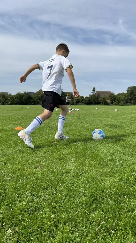 Player striking the ball on a grass pitch