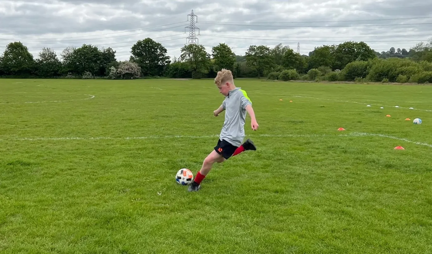 Young player striking a football during a 1-2-1 session
